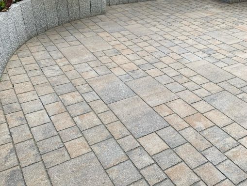 Kreuzend gepflasterter Bereich mit rechteckigen Steinen in verschiedenen Grautönen.