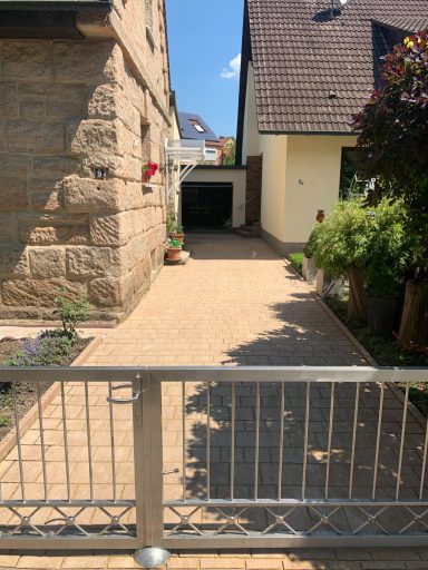 Zwei Gebäude mit einem gepflasterten Weg und einem Tor im Vordergrund.