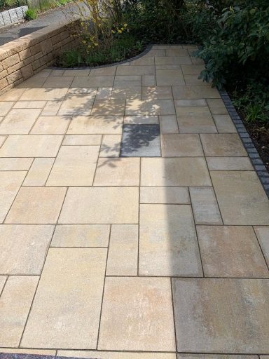 Gestaltete Pflasterfläche mit verschiedenen Steinformaten und Schattenwurf.